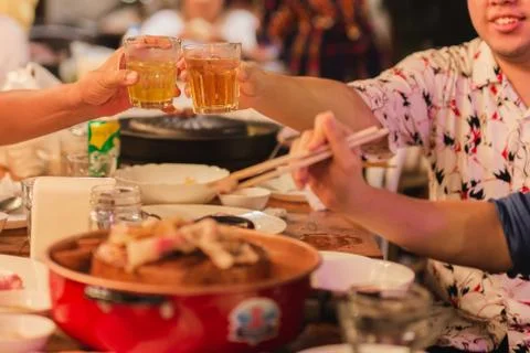 Short in low light man clinking glasses with alcohol celebrating family dinner. Stock Photos