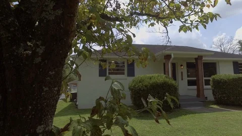 Short pan through trees on painted brick home Stock Footage 97721996