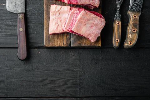 Short Ribs Bone In stew, and old butcher cleaver knife, on black wooden table Stock Photos