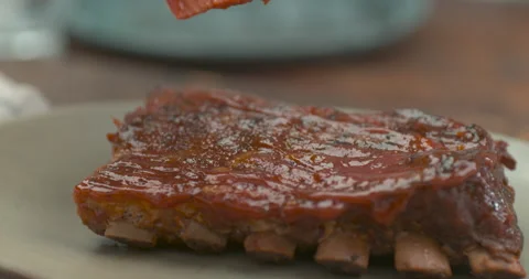 Short ribs get glazed with brush with sweet barbeque sauce in ultra slow motion Stock Footage 199461867