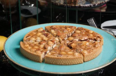 Shortbread cake with nuts and caramel on a blue plate on a dark background Stock Photos