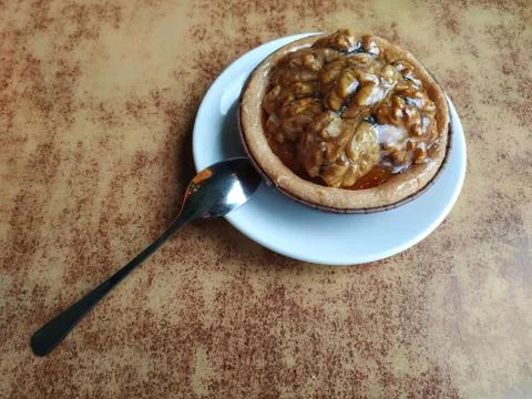 Shortbread with caramel and walnuts on the table in a white saucer and a spoo Stock Photos