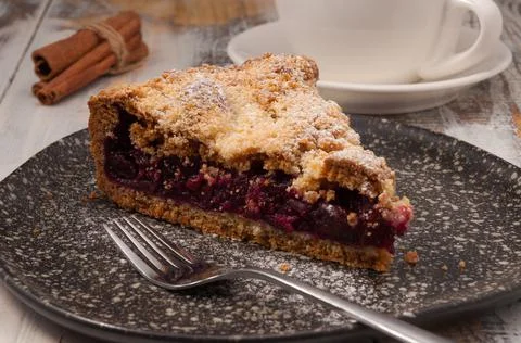 Shortbread cherry pie on a dark plate with a Cup of tea Foto stock