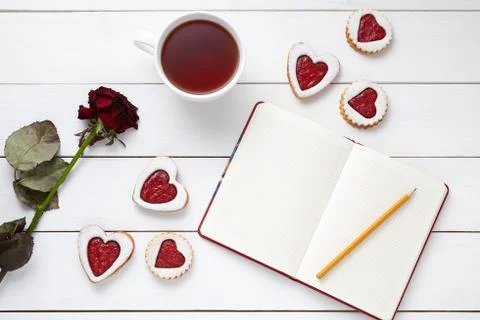 Shortbread heart shaped cookies with empty notebook, pencil, cup of tea and rose Stock Photos