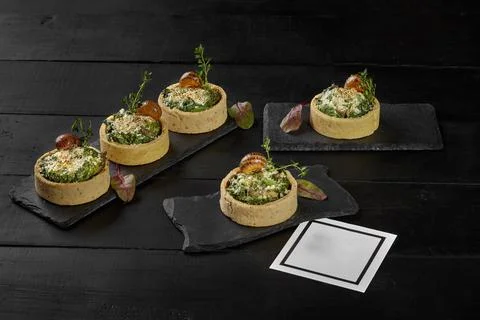Shortbread tartlets with cream cheese, spinach and snails Stock Photos