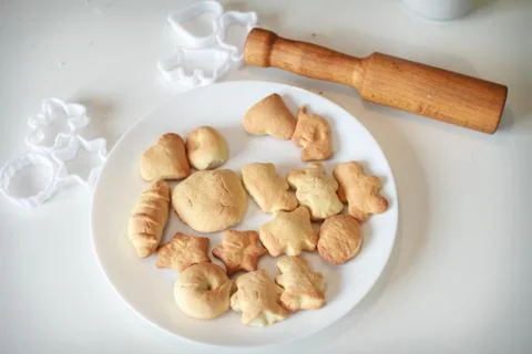 Shortbread on a white plate on a white background. Rolling pin and cookie cut Foto stock