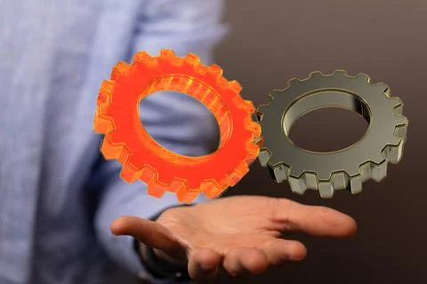 Shot of 3d models of orange and gray cogwheels over a human hand Stock Photos