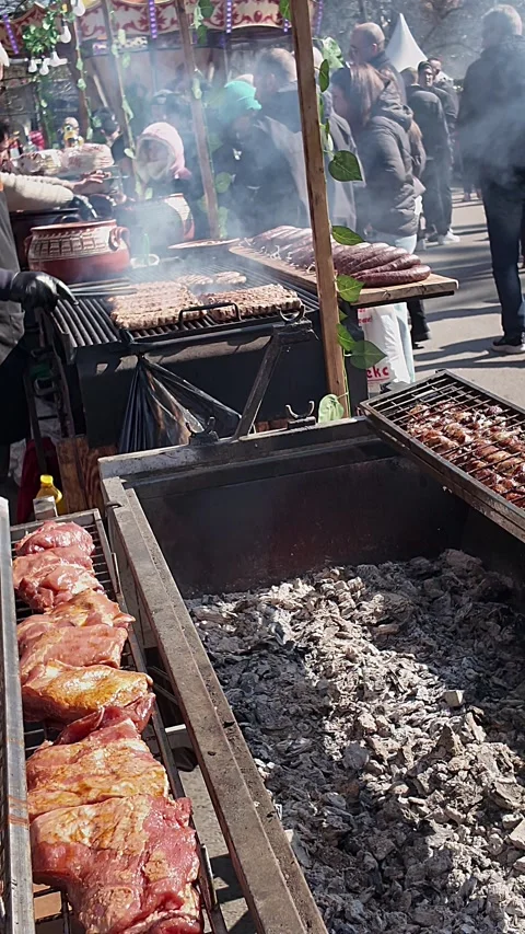 Shot above rotating meat grill revealing people queuing at smoky family Stock Footage 331409529