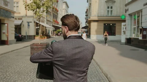 Shot back of handsome bearded man use phone walking on city street look around Stock Footage 140479504