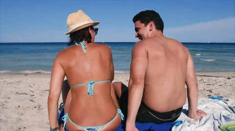 Shot from behind of couple at beach talking and laughing looking at ocean Stock Footage 66729609