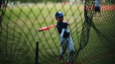 Shot from behind net of a Kid Practicing his Batting Stock Footage 47490444