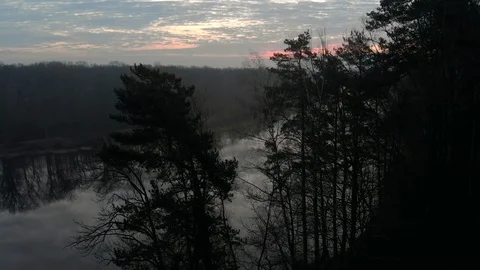Shot from behind the trees dawn over the bend of the river in the morning of Stock-Footage 127807995