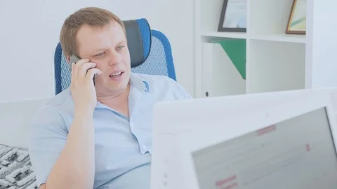 Shot of a businessman using a desktop pc while talking on mobile phone Stock Footage 90448005