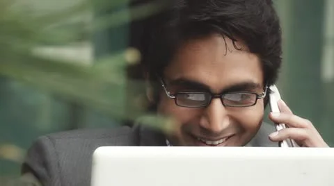 Shot of a businessman using a laptop while talking on mobile Stock Footage