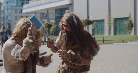 Shot of caveman in animal fur using modern tablet browsing internet having fun Stock Footage 118396530