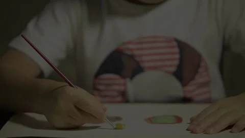 Shot close-up of a child's hand with a brush painting with watercolor on a pa Stock Footage 135605152