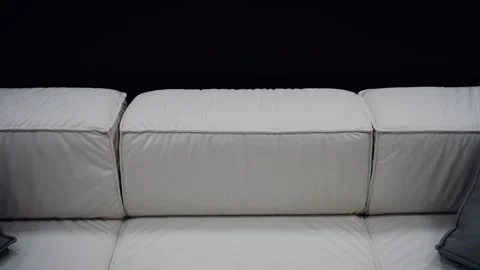 Shot of a comfortable white sofa with two gray pillows on a black background. 4k Stock Footage 232056024