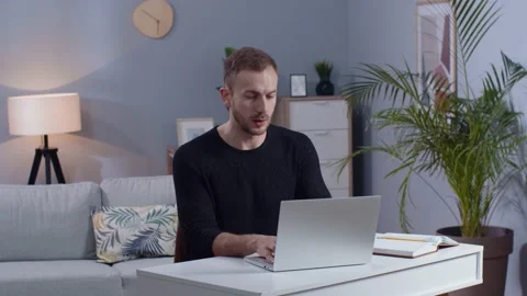 Shot of concentrated young man working on laptop in living room. Guy with beard Stock Footage 189030432