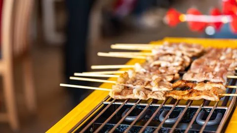 The shot of a cook grill Moo Ping or grilled pork skewers in Thai style on .. Foto stock