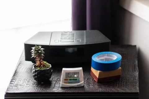 A shot of a dark bedside table with items such as a cactus scotch tape and an Stock Photos