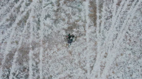 Shot on a drone. A man digs the ground with a shovel and looks for metal. Video stock 221164957