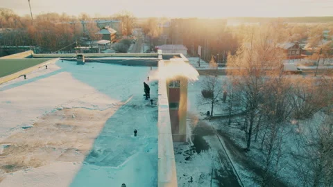 Shot on a drone. A man throws snow off the roof. Snow cleaner. Stock Footage 221751813