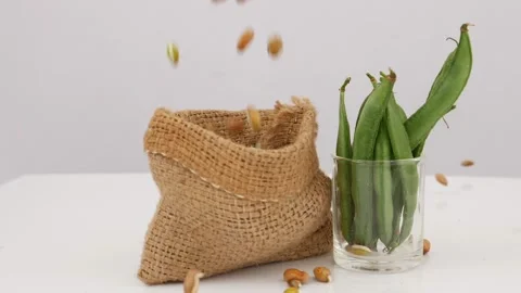 Shot of falling bean seeds on brown jute bag, Glass filled with green beans Stock Footage 159638293