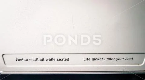 Shot of fasten seat belts sign on tray table in flight Stock Photos