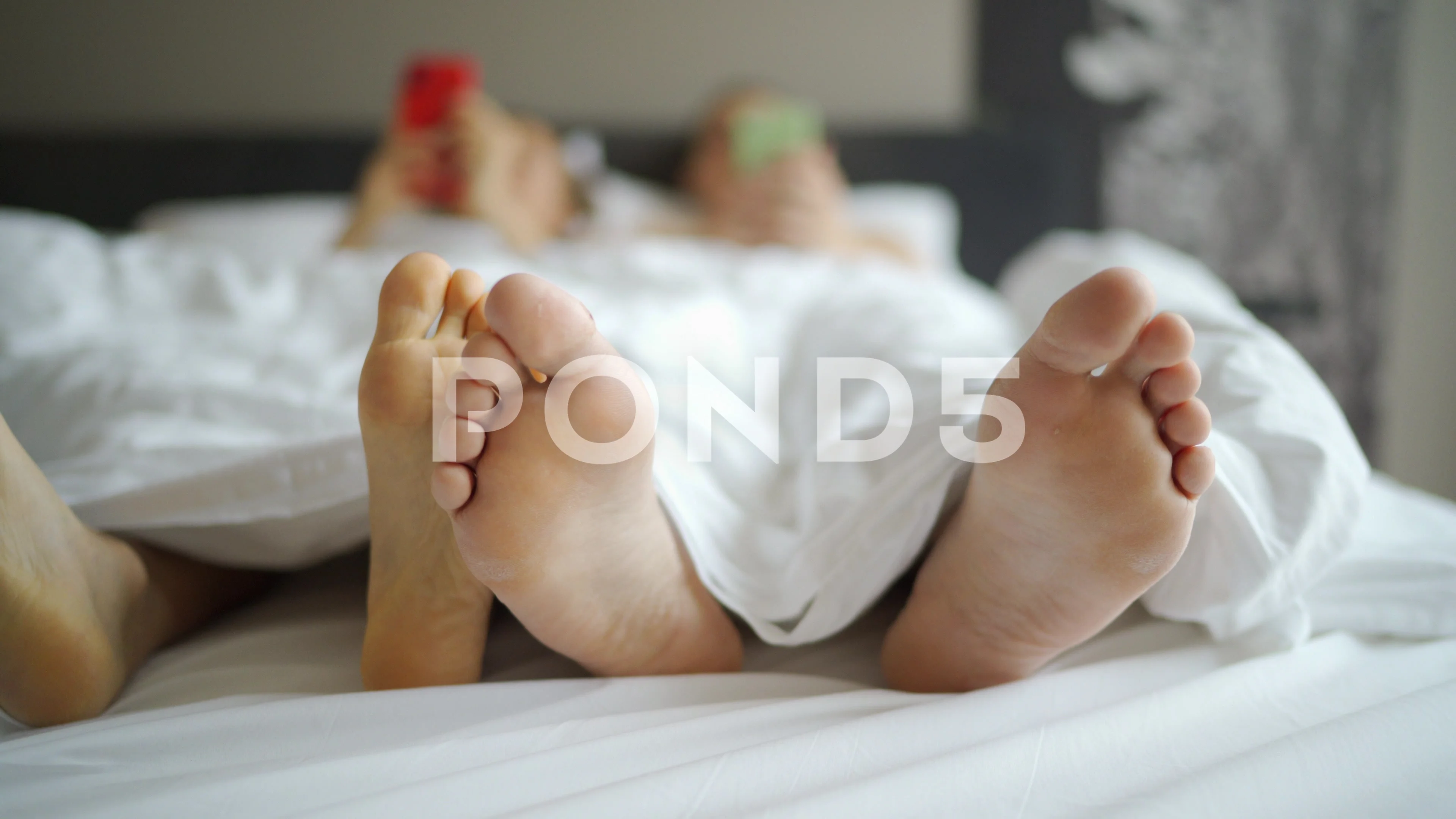 Shot of feet boyfriend and girlfriend lying in bed under blanket.