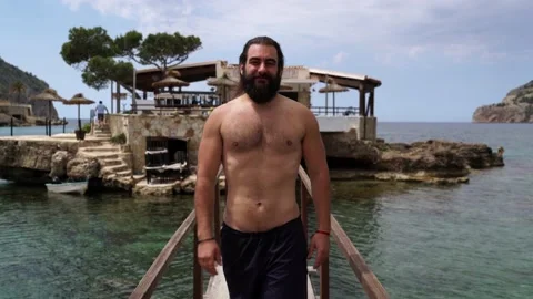 Shot of a fitted bearded man walking on a brigde at Camp de Mar beach (Mallor 스톡 동영상 131152505