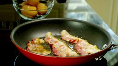 A shot of fresh bacon slices being flipped on a frying pan. 스톡 동영상 334642946