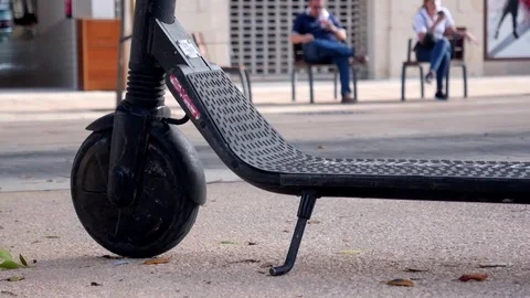 Shot of the front wheel of an electric shared scooter parked on a busy street Stock Footage 117509250