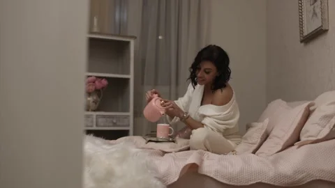 Shot of a girl preparing tea while she is on her bed Stock Footage 168128721
