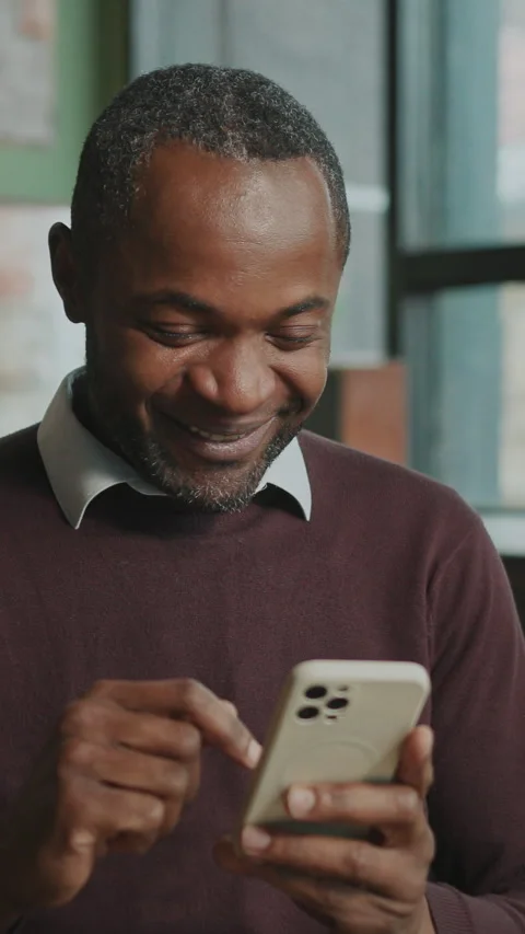 Shot of happy good-looking relaxed African man drinking coffee and texting on Stock Footage 281342224
