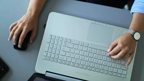 Shot from a height female using a lap-top keyboard and mouse Stockbeeldmateriaal 156784131