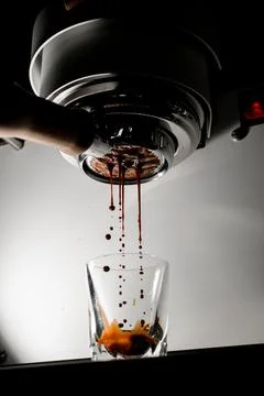Shot of hot espresso coffee is pulled through portafilter into clear glass. Stock-Fotos