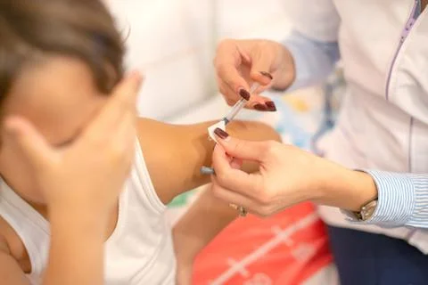 Shot of human hands making an injection with a syringe to a little girl who i Stock Photos