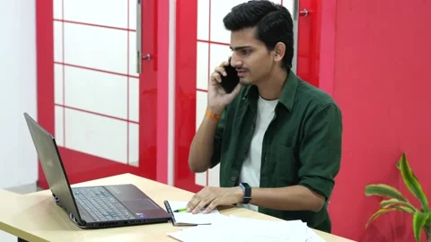 Shot of an Indian Boy doing work discussion over a phone call in office Stock Footage 228536333