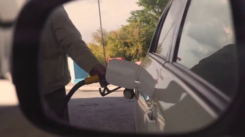 Shot of insertion of the nozzle and pumping gasoline into a white vehicle at the Stock Footage 80279773
