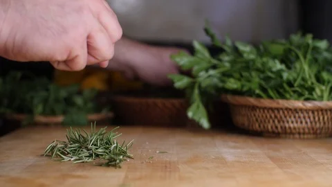 Shot of man chef cutting dice Rosemary leafs on chopping wooden board Stock Footage 85489169