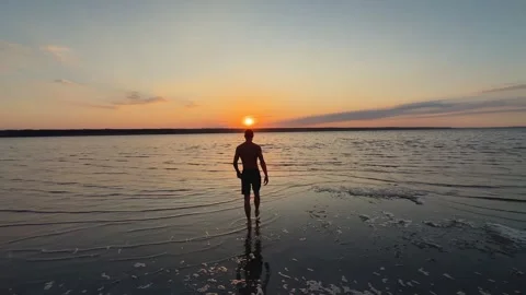 Shot of Man Walking on Estuary Beach at Sunset Stock Footage 342135042