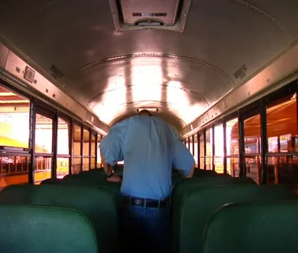 Shot of man walking through empty schoolbus Stock Footage 21623971