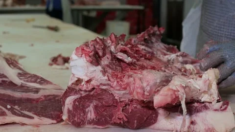 Shot of meatman with a sharp knife in hand separating meat from bones. 4k Stock Footage 144112641