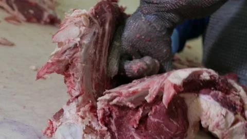 Shot of meatman with a sharp knife in hand separating meat from bones. 4k Stock Footage 144112832