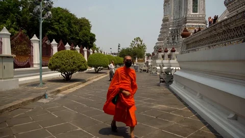 A shot of a monk walking through a shot of a recording of Wat Arun Stock Footage 128241111