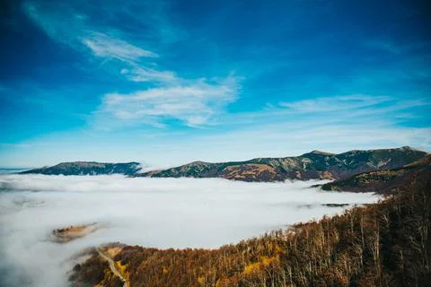 Shot of a mountain peeks above the clouds Stock Photos