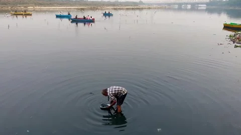 Shot of Poor Man finding money in river at Yamuna Ghat, Delhi Vídeos de archivo 299789720
