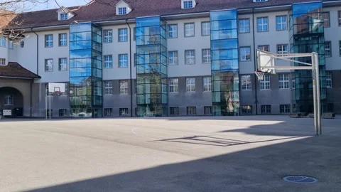 Shot of the quiet backyard of Pestalozzi School, featuring an empty basketball Stock Footage 306140656