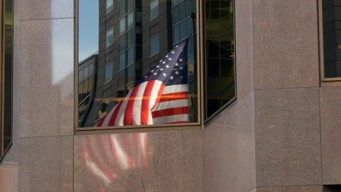A shot of the reflection of a USA flag flying in a window Stock Footage 87341147