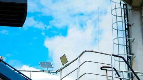 Shot of a ship upper deck railing featuring a small solar panel and an LED fl Stock Photos